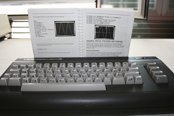 Commodore 16 - Ordenador con el manual abierto, mostrando algunos de los ejemplos de generación de gráficos en BASIC